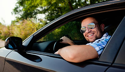 Man sitting in new car smiling with pride.