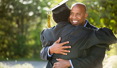 Man hugging his son after college graduation.