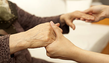 Person assisting an elderly person to stand.