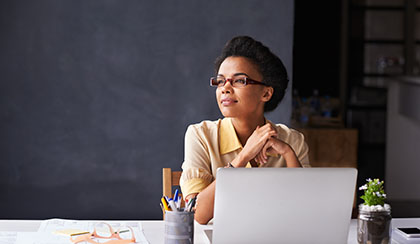 Female day dreaming or thinking while using laptop.