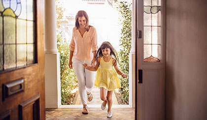 Mother and child holding hands running through front door